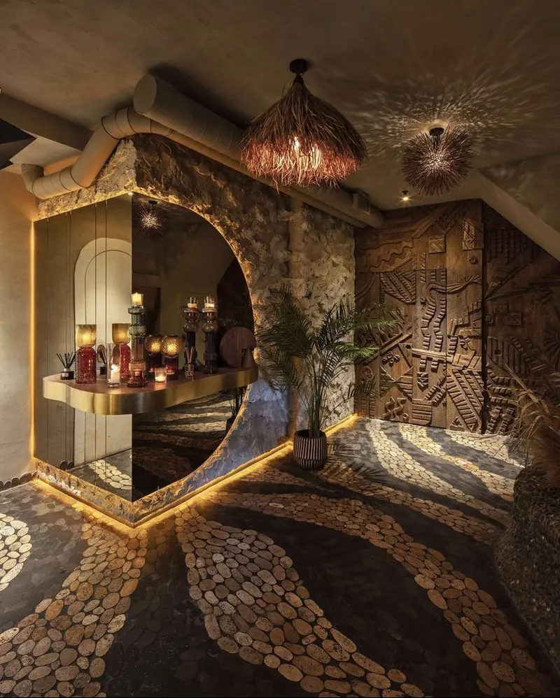 An arched passage with carved wood panels and a pebble mosaic floor lit in gold